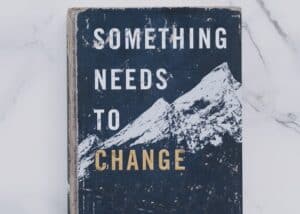 Kuvassa on kirja, jossa lukee: " Something needs to change".